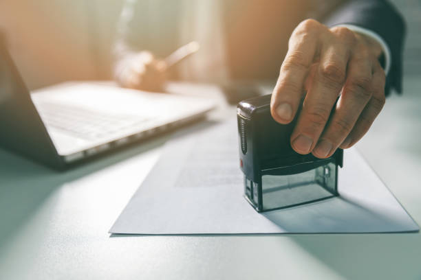 zakenman zet een stempel op zakelijke contract in office - autoriteit stockfoto's en -beelden