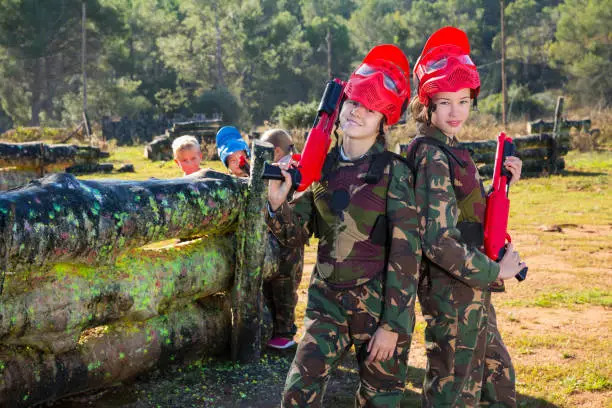 Photo of two girls paintball players with marker guns ready for game