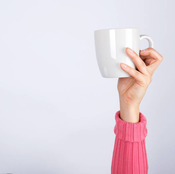 istock female hand in a pink sweater holds a gray ceramic cup, white background 1184640827
