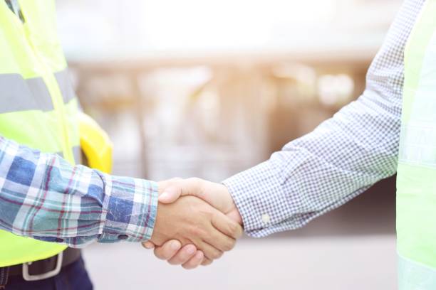 istock Construction workers in helmets and protective clothing are holding hands with supervisors while working in the office center 1184643165
