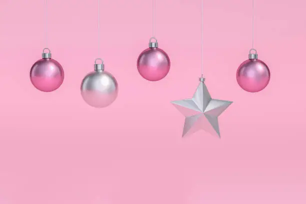 Photo of Outstanding silver star shaped hanging among pink and white christmas ball Ornaments hanging on pastel pink background