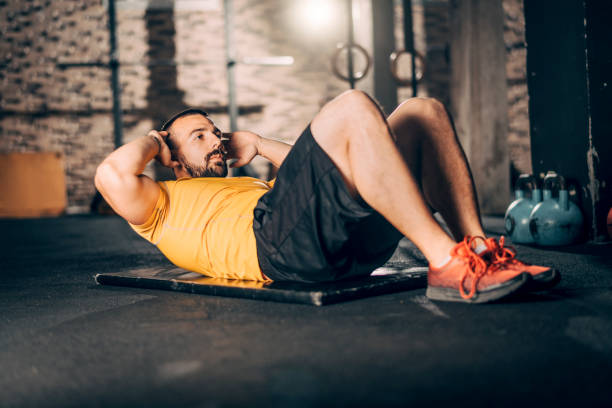 istock Young muscular athlete doing a sit ups workout in a   gym 1184648094