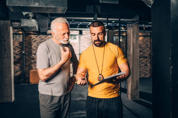 istock Personal trainer showing a workout plan to an active senior man in a   gym 1184650024