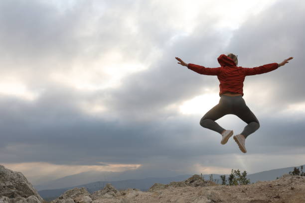 istock Young female trail runner in mid-air jump on mountain ridge 1184650129