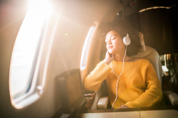 개인 제트기에 앉아 헤드폰을 통해 음악을 듣고 젊은 유행 여성 - upper class audio 뉴스 사진 이미지