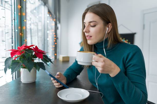 Young woman resting at break in cafe with cup of hot drink