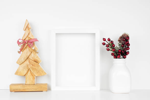 istock Mock up white frame with wooden Christmas tree and branch decorations on a shelf against a white wall 1184659060