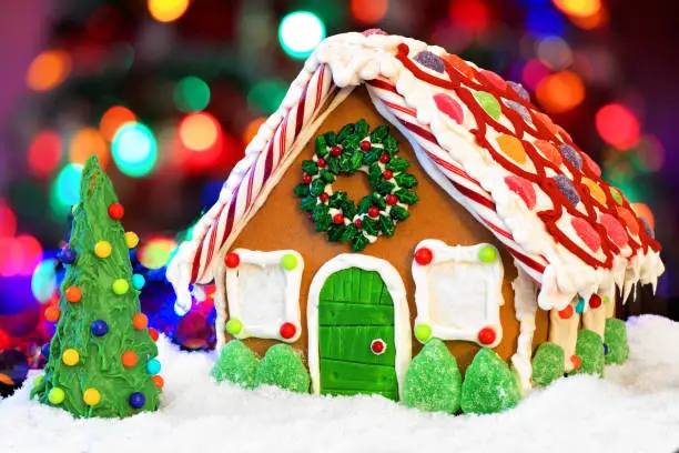 Christmas gingerbread house with candy tree against a colorful twinkling light background