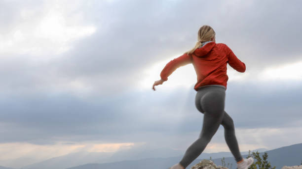 istock Young female trail runner crosses mountain ridge at sunrise 1184661109