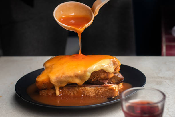 Pouring gravy over a Francesinha sandwich