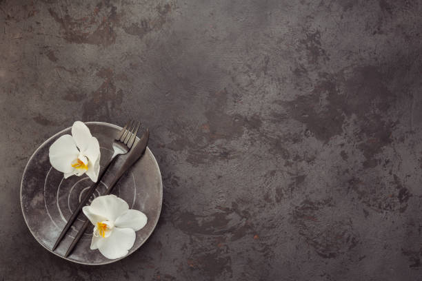 istock Elegance table setting with knitted grey napkin, cutlery, ceramic plates, glasses and white orchid flowers 1184667532