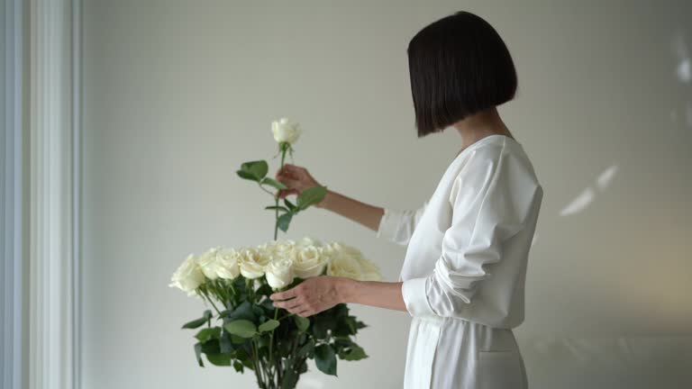 Stylish woman puttting flowers on the table