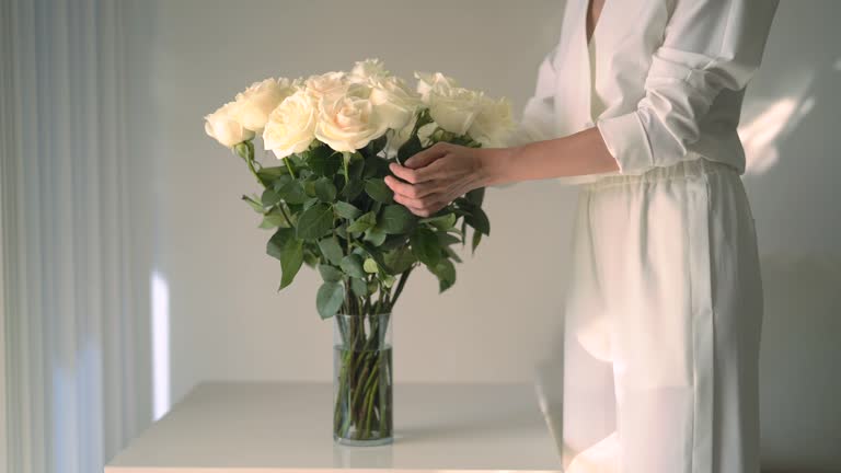 Stylish woman puttting flowers on the table