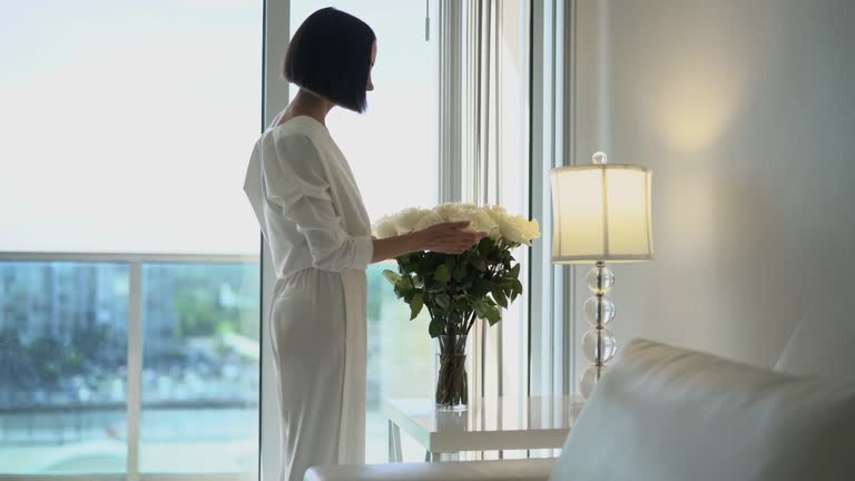 Stylish woman puttting flowers on the table