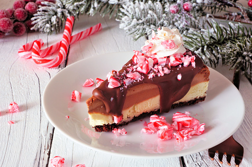 Christmas holiday candy cane chocolate cheesecake. Side view scene with a white wood background.