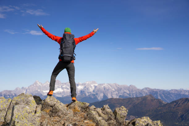 istock back view one mountainer man on mountain peak with open arms 1184672258