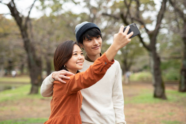 istock Young couple taking selfie in park 1184673375