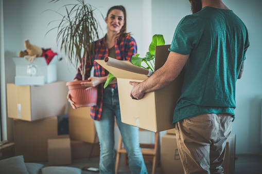 An attractive, young couple unpacking moving boxes in an unfurnished apartment.