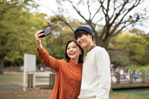 istock Young couple taking selfie in park 1184673420