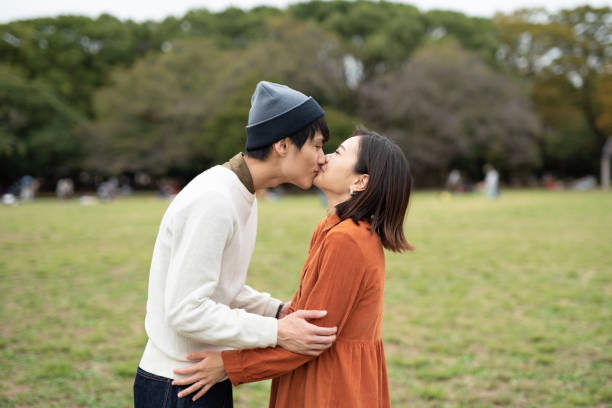istock Young couple kissing in park 1184673443