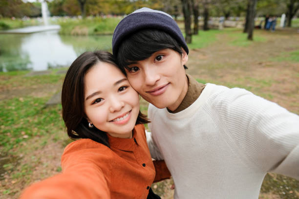 pareja joven tomando selfie en el parque - autorretrato fotografías e imágenes de stock