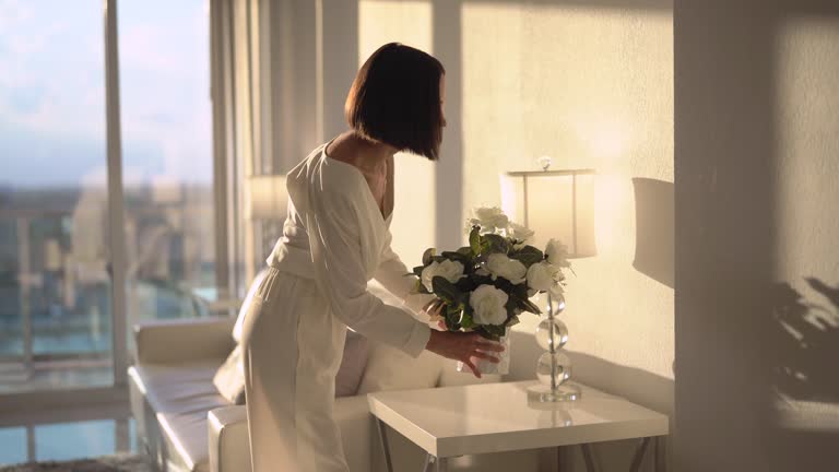 Stylish woman puttting flowers on the table