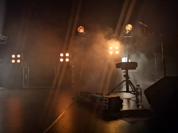 escenario de concierto sesión y accesorios de iluminación en él, equipo musical. el humo de una instalación de humo rompe suavemente la luz amarilla y crea el efecto de un brillo suave. - entre bastidores fotografías e imágenes de stock