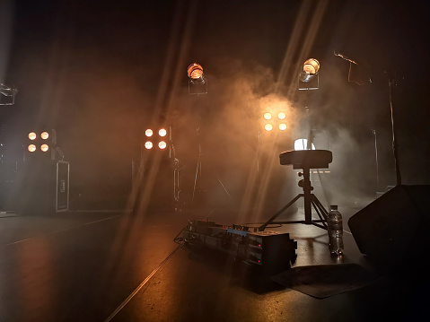 Smoke from a smoke installation gently breaks yellow light and creates the effect of a gentle glow. Concert stage and lighting fixtures on it, musical equipment.