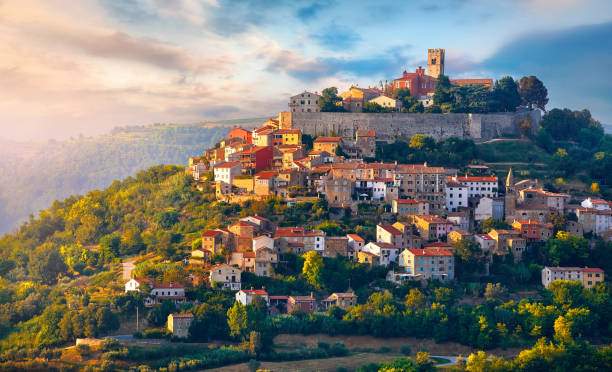 Antique city Motovun Croatia Istria. Picturesque panorama Antique city Motovun Croatia Istria. Picturesque panorama age-old village at hill with pink cloud and sunny light and authentic home with red tegular roof and green vineyard garden. istria photos stock pictures, royalty-free photos & images
