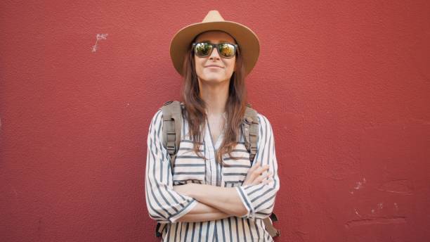 retrato de mujer turista hipster frente a la pared roja. mujer con blusa despojada y sombrero de paja - people personal accessory town hat fotografías e imágenes de stock