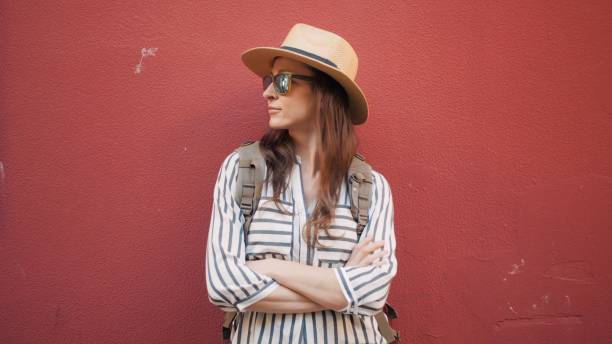 retrato de mujer turista hipster frente a la pared roja. mujer con blusa despojada y sombrero de paja - people personal accessory town hat fotografías e imágenes de stock