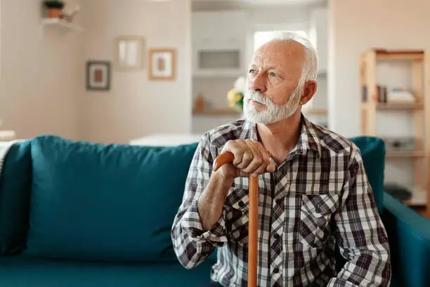 Close up Portrait of a thoughtful senior man with beard at home in the living room looking away