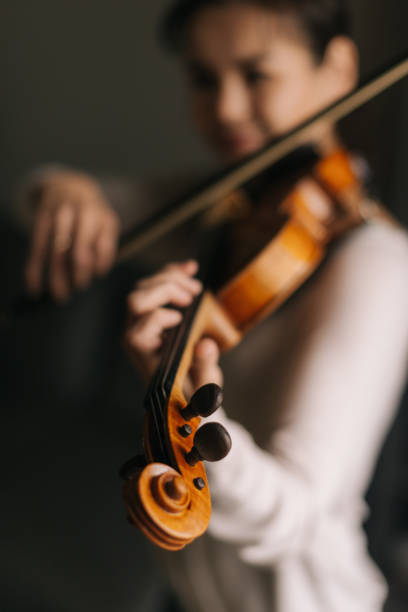 schöne junge frau spielt geige in ihrem haus - practicing music violin women stock-fotos und bilder