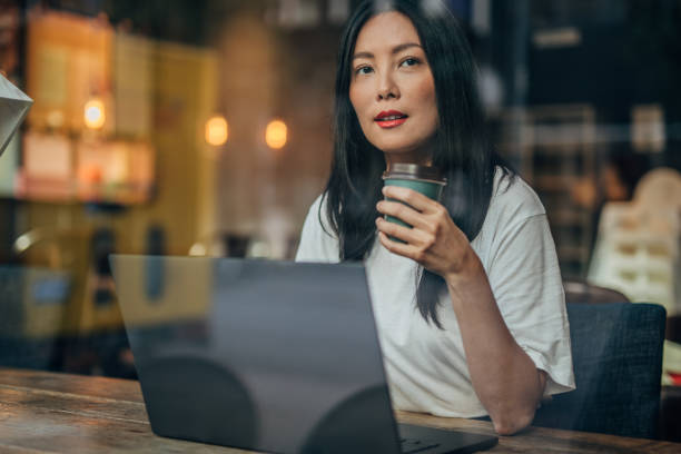 istock Pretty woman drinking coffee and using laptop 1184697206