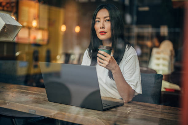 istock Beautiful woman drinking coffee and using laptop 1184698286