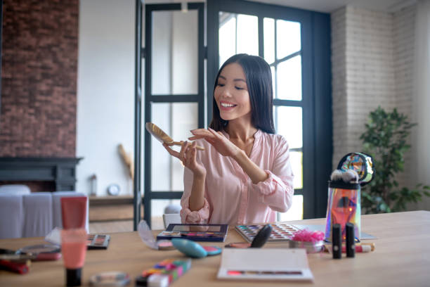 istock Smiling woman taking powder while starting to do makeup 1184699081