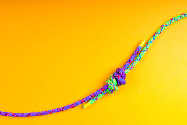 The grapevine node made of two colorful ropes on yellow background.