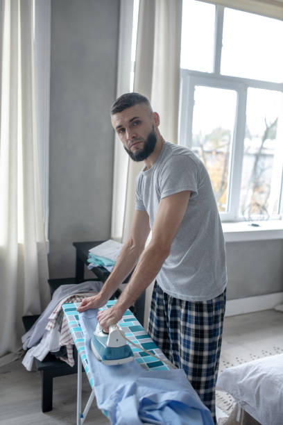 istock Dark-haired young businessman ironing in the morning 1184704734