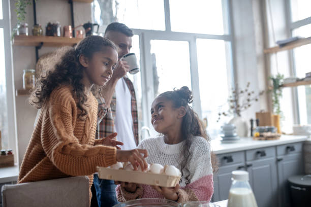 istock Cute sister giving eggs while cooking traditional family pie 1184704747