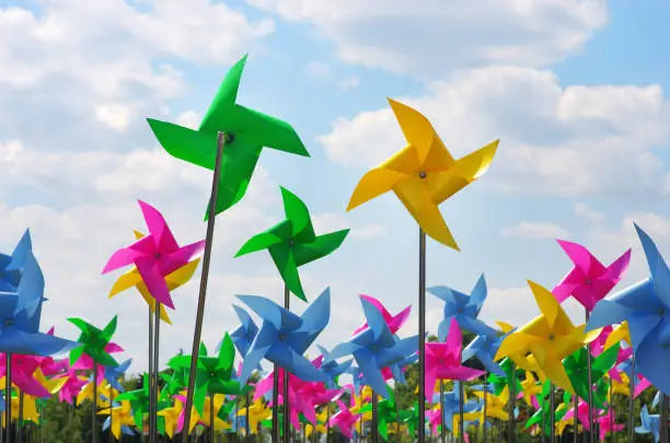 Photo of Colourful children's pinwheels in the blue sky with clouds