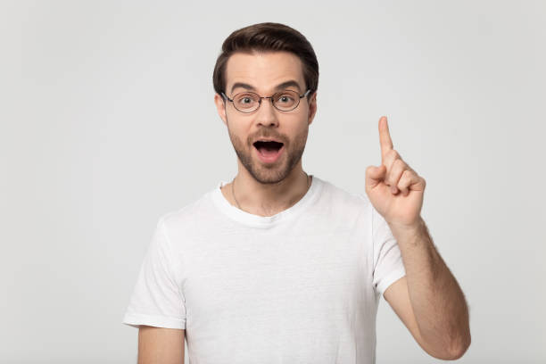 istock Surprised happy millennial man rising finger up on empty copyspace. 1184709928