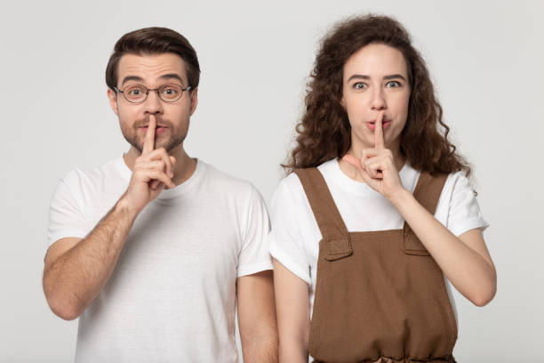 istock Mysterious young friends looking at camera, making hush gesture. 1184709981