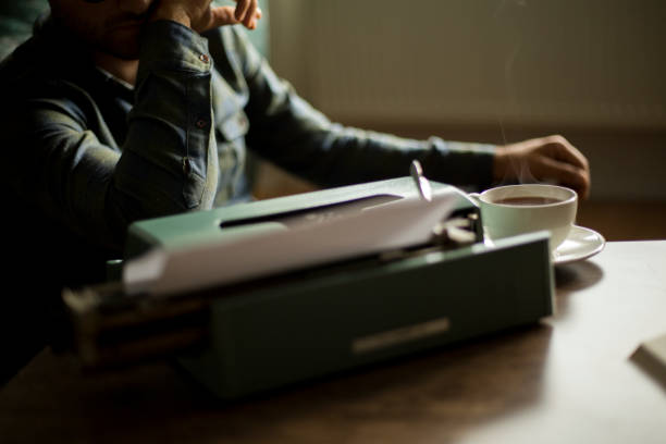 male hands writing with an old blue typewriter, vintage stock photo