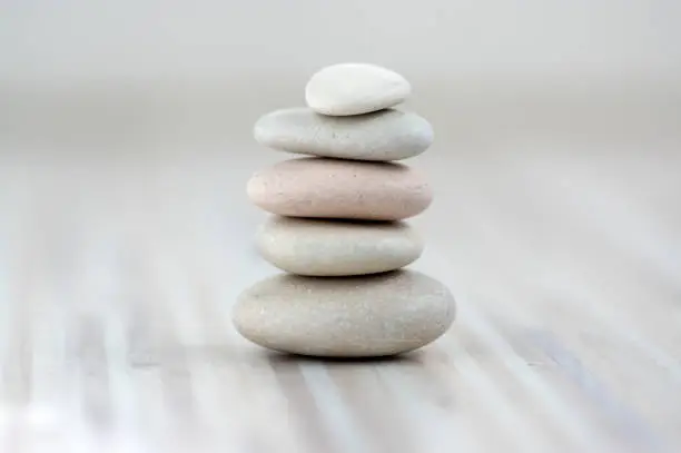 Photo of Harmony and balance, cairns, simple poise stones on wooden light white gray background, simplicity rock zen sculpture