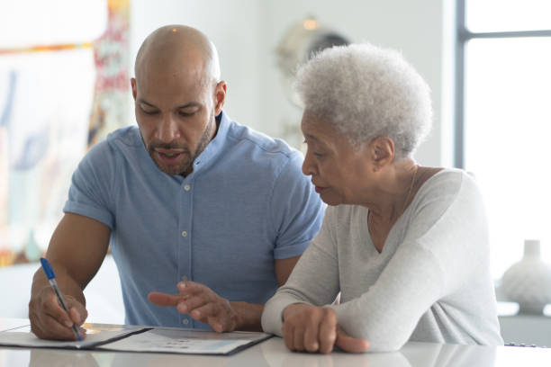 un consulente afroamericano maschio incontra una foto d'archivio di un cliente senior femminile - retirement senior adult planning finance foto e immagini stock