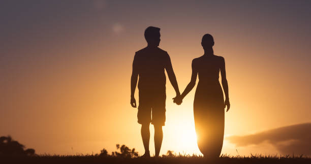 istock Young couple walking together at sunset 1184718500