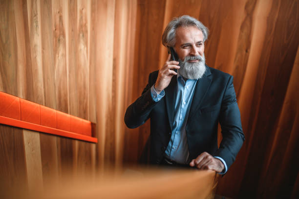 istock Senior Bearded Businessman Using Smart Phone on Staircase 1184729539