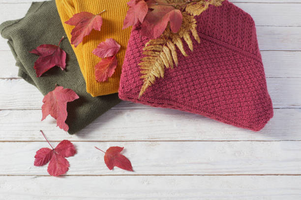 istock stack of sweaters with autumn leaves  on  white wooden table 1184729886