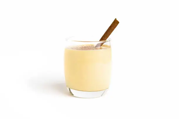 Homemade traditional Christmas eggnog drinks with ground nutmeg and cinnamon in the glass isolated on white background