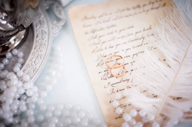 istock Wedding rings on a piece of note on a white pen background 1184732350